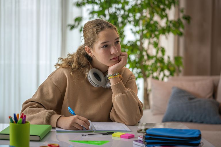Tonåring vid skrivbordet som tappat fokus från läxorna