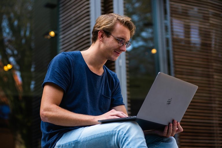 Ung vuxen som sitter med sin laptop en kväll